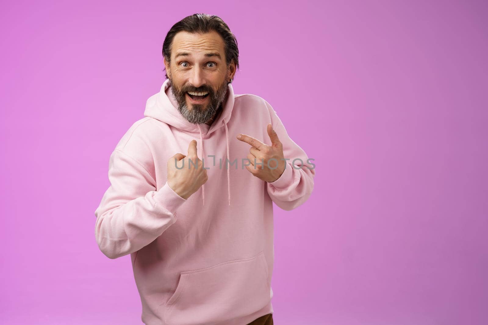 Excited surpried caucasian bearded guy pointing himself amazed questioned cannot believe was picked chosen standing thrilled purple background become winner lottery wearing pink hoodie by Benzoix