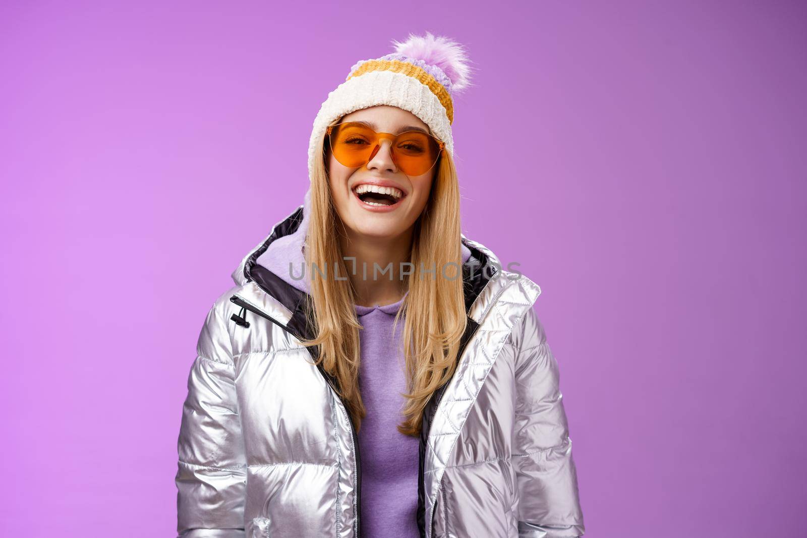 Stylish friendly charismatic blond woman in silver shiny jacket hat sunglasses ready learn snowboarding smiling laughing happily having fun snowy recreation resort, standing purple background by Benzoix