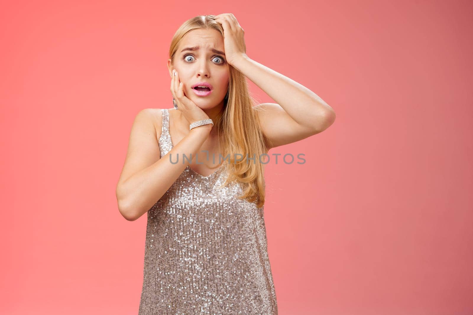 Shocked frightened insecure panicking woman blond hairstyle in silver dress touch head pop eyes afraid scared seing terrifying crime standing stupor speechless gasping shook, red background by Benzoix