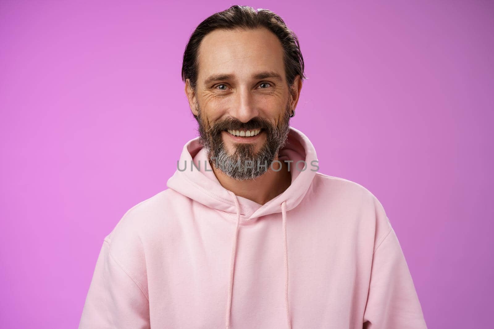 Waist-up happy cheerful caucasian bearded man grey hair in pink trendy hoodie smiling broadly feel healthy attend gym lead active lifestyle grinning white perfect teeth, standing purple background by Benzoix