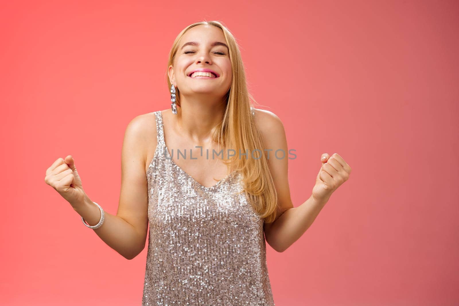 Sweet taste win. Charming happy blond girl rejoicing triumphing raise head up close eyes smiling broadly clench fists victory celebration gesture achieve dream come true, standing red background.