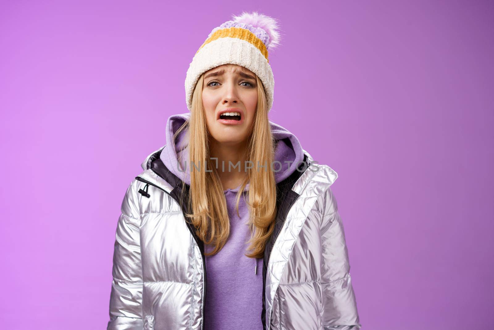 Upset sobbing miserable cute blond woman in silver stylish jacket hat crying whining unhappy feel sadness distress look disappointed complaining cruel life, unlucky standing purple background.