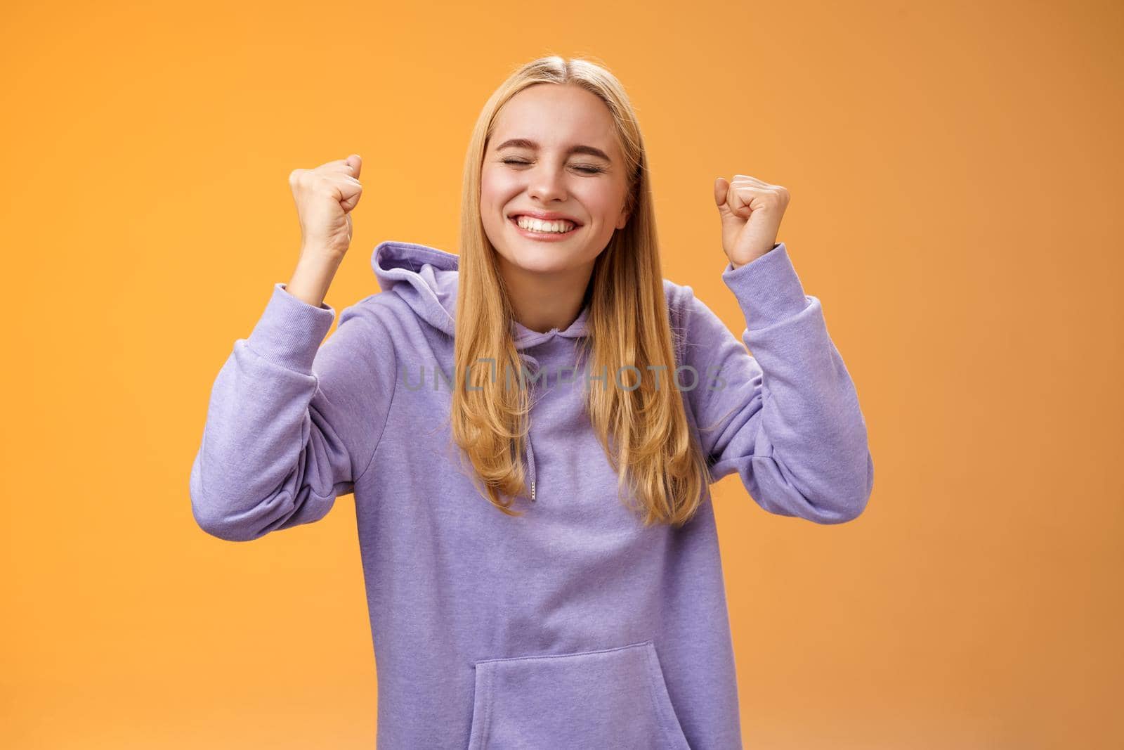 Triumphing celebrating positive fair-haired young female winner raise hands clench fists up victory achievement gesture close eyes smiling broadly gladly accepting great offer, accomplish success by Benzoix