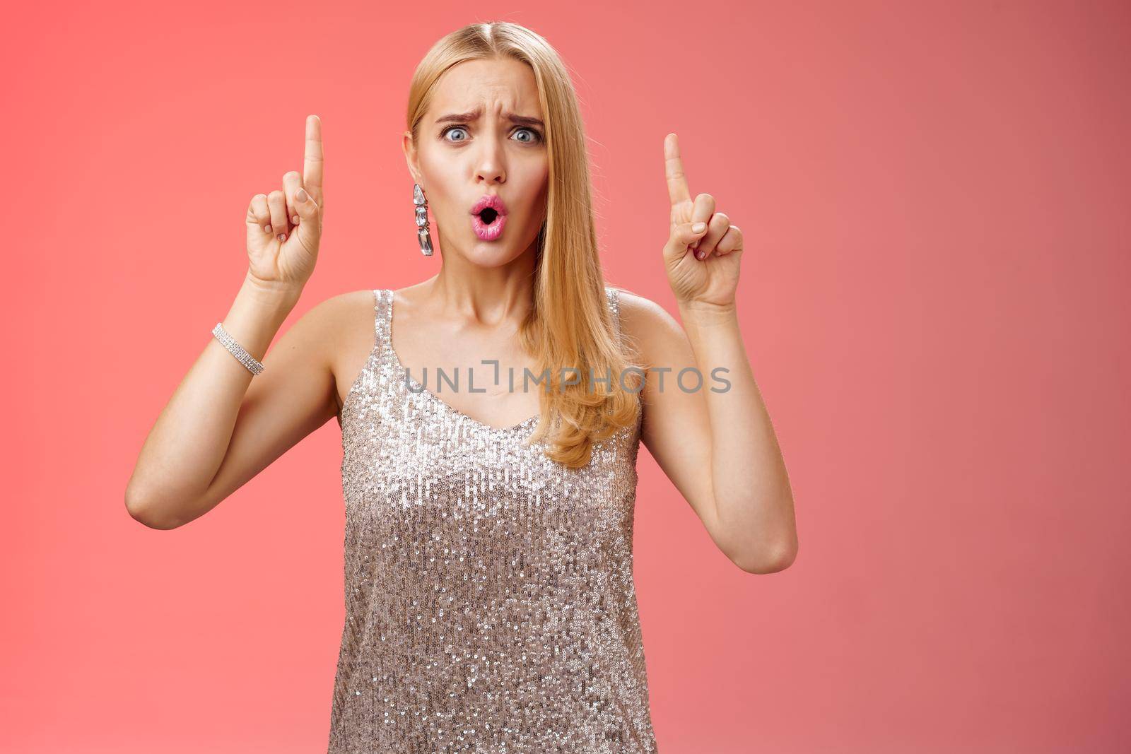 Upset gloomy complaining blond whining girl in silver stylish luxurious dress frowning cringing unhappy pointing up regret jealous tell boyfriend sale over, standing depressed sad red background by Benzoix
