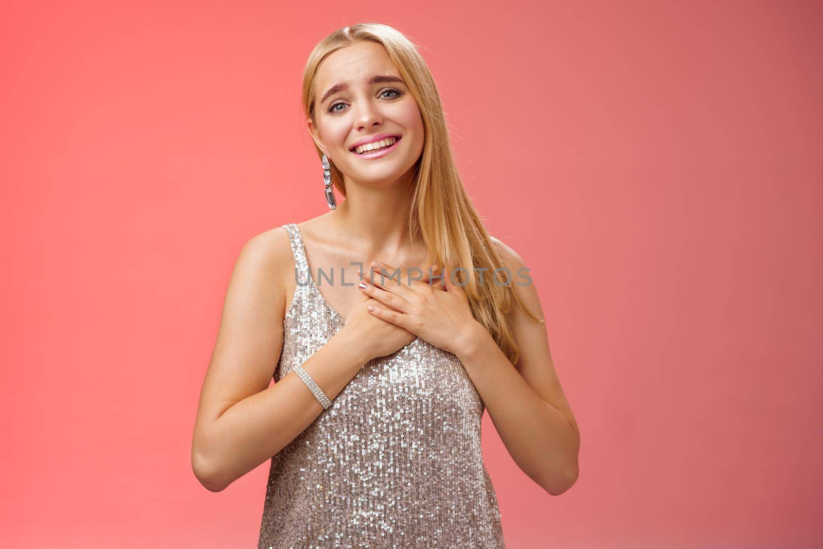 Touched delighted charming blond woman receive heartwarming pleasant gift smiling glad press palms heart moved thanking cherish romantic move boyfriend made, standing red background by Benzoix