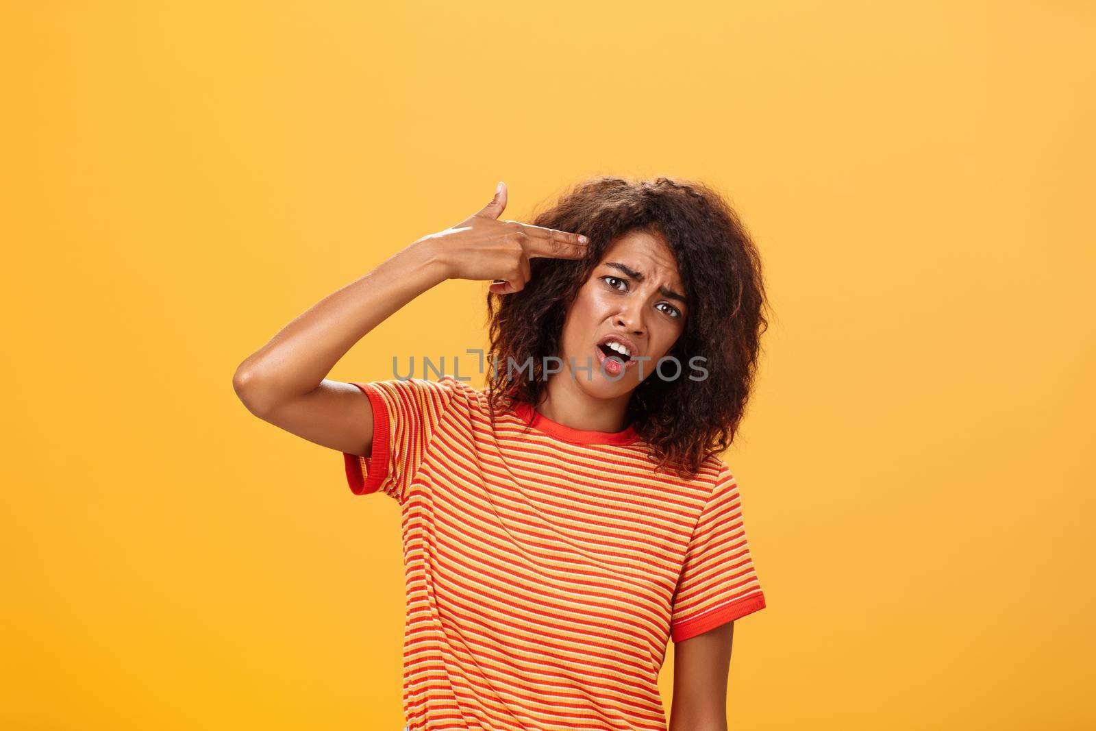 I would rather kill myself. Displeased bored and dissatisfied attractive bothered girlfriend in striped t-shirt tilting head, grimacing from dislike putting finger gun to forehead, commiting suicide. Copy space