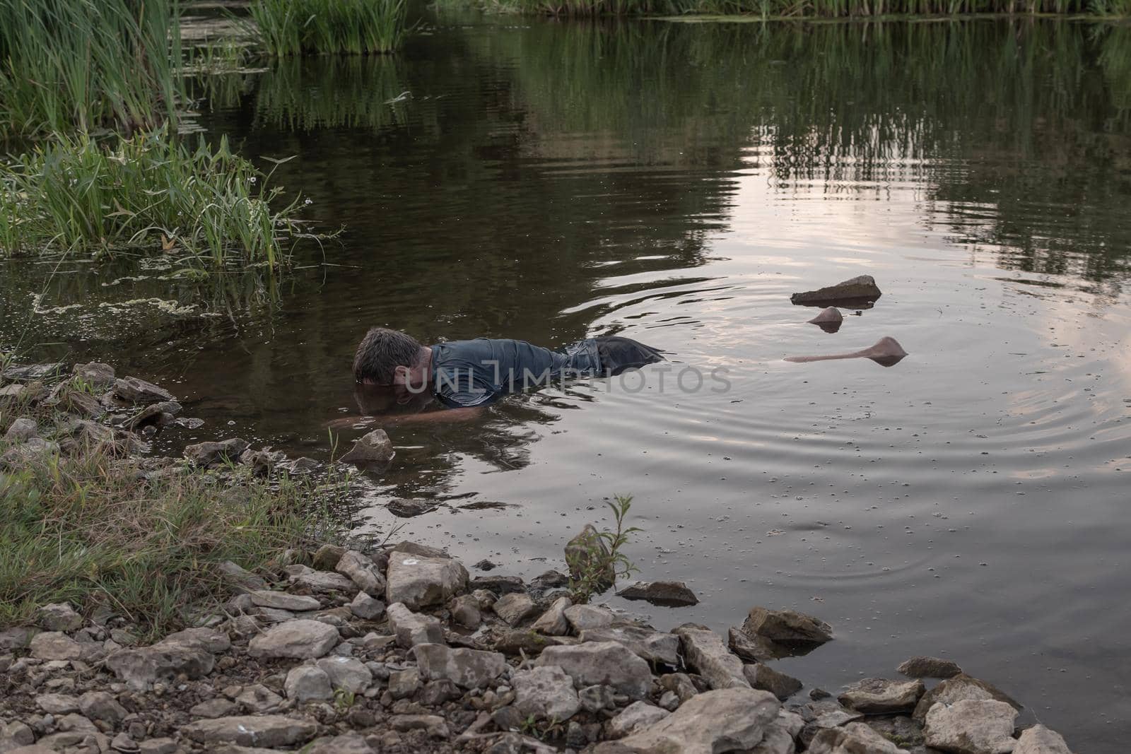 the body of a man who drowned lies face down in the water, the lifeless body of a murdered young man on the river by studeg83