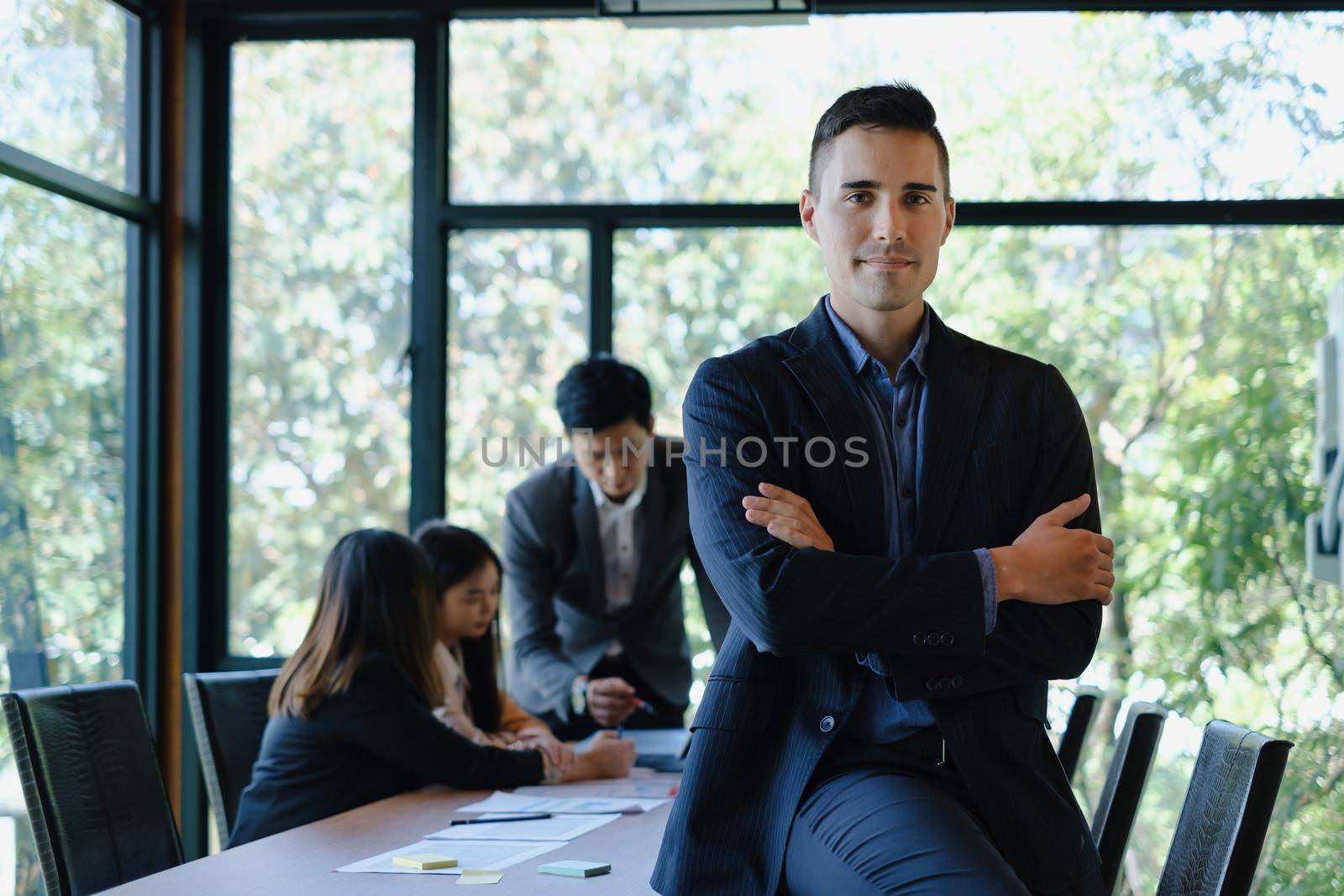 Portrait of a handsome CEO cross arm in office with business team working on background