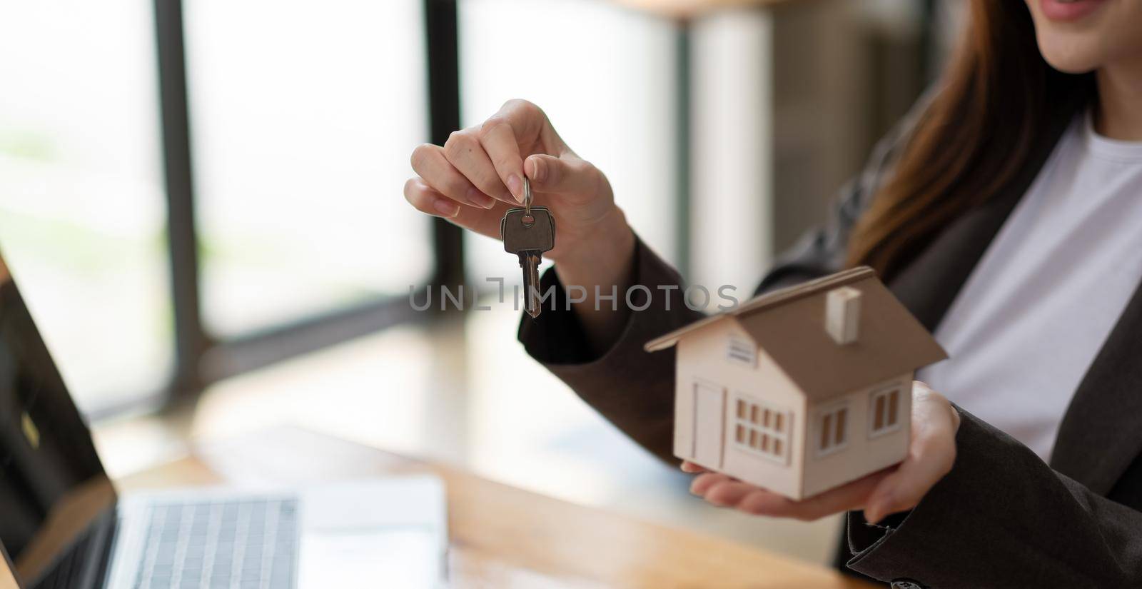 Real estate agent hand holding house model and keys.