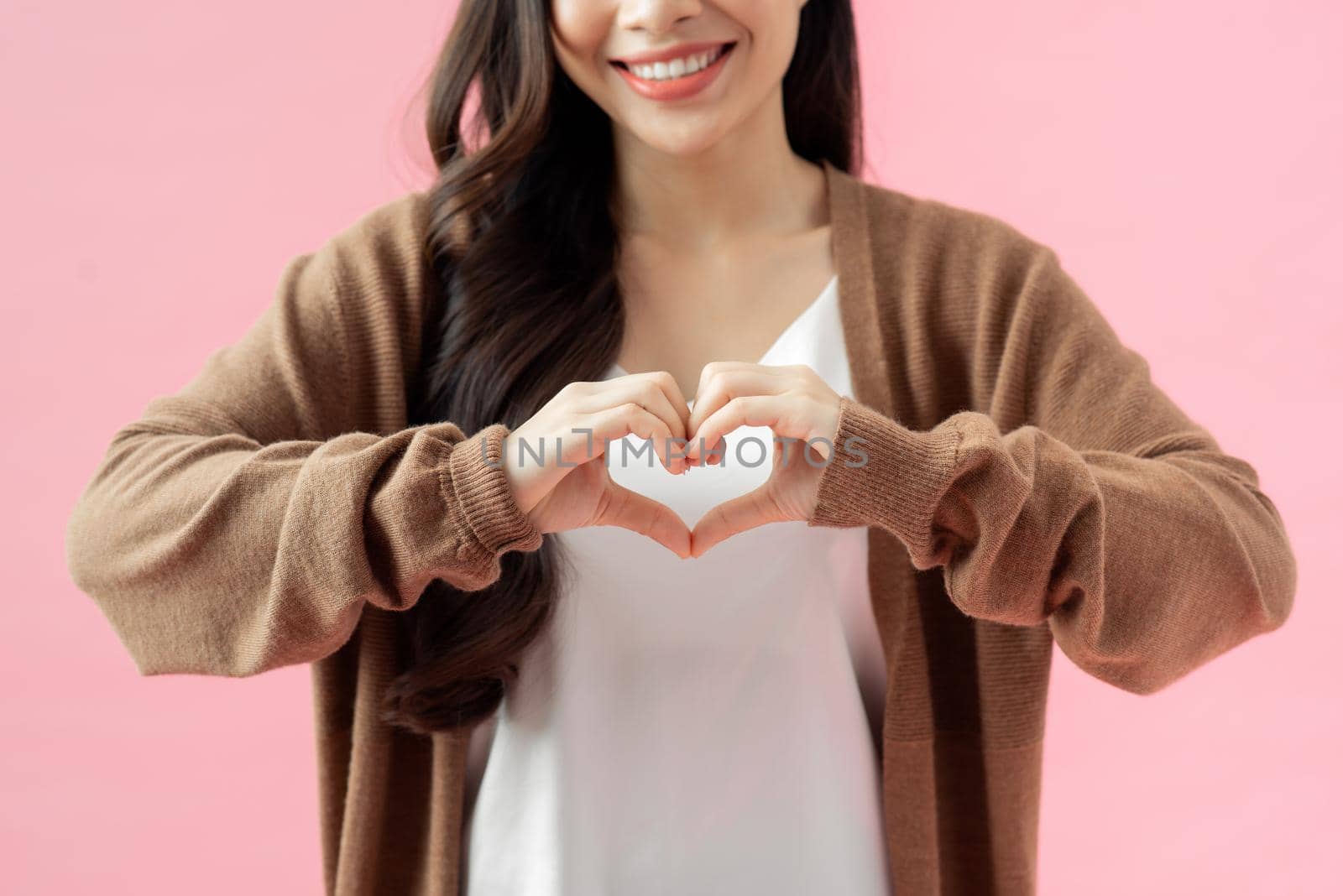 young woman who makes a heart shape by her hand.