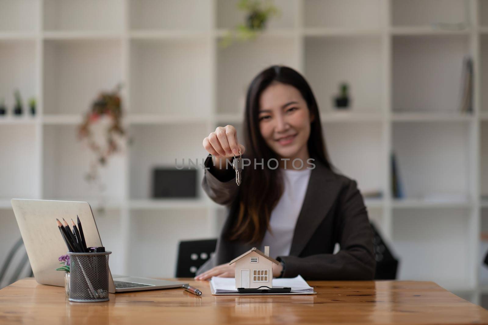 Real estate agent hand holding house model and keys.