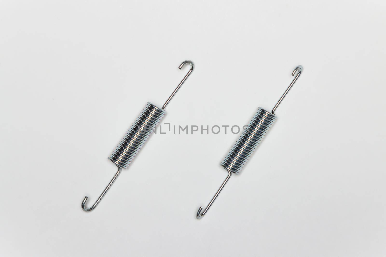 Two long springs for repairing the brakes of the machine. Set of spare parts for car brake repair. Details on white background, copy space available. UHD 4K.