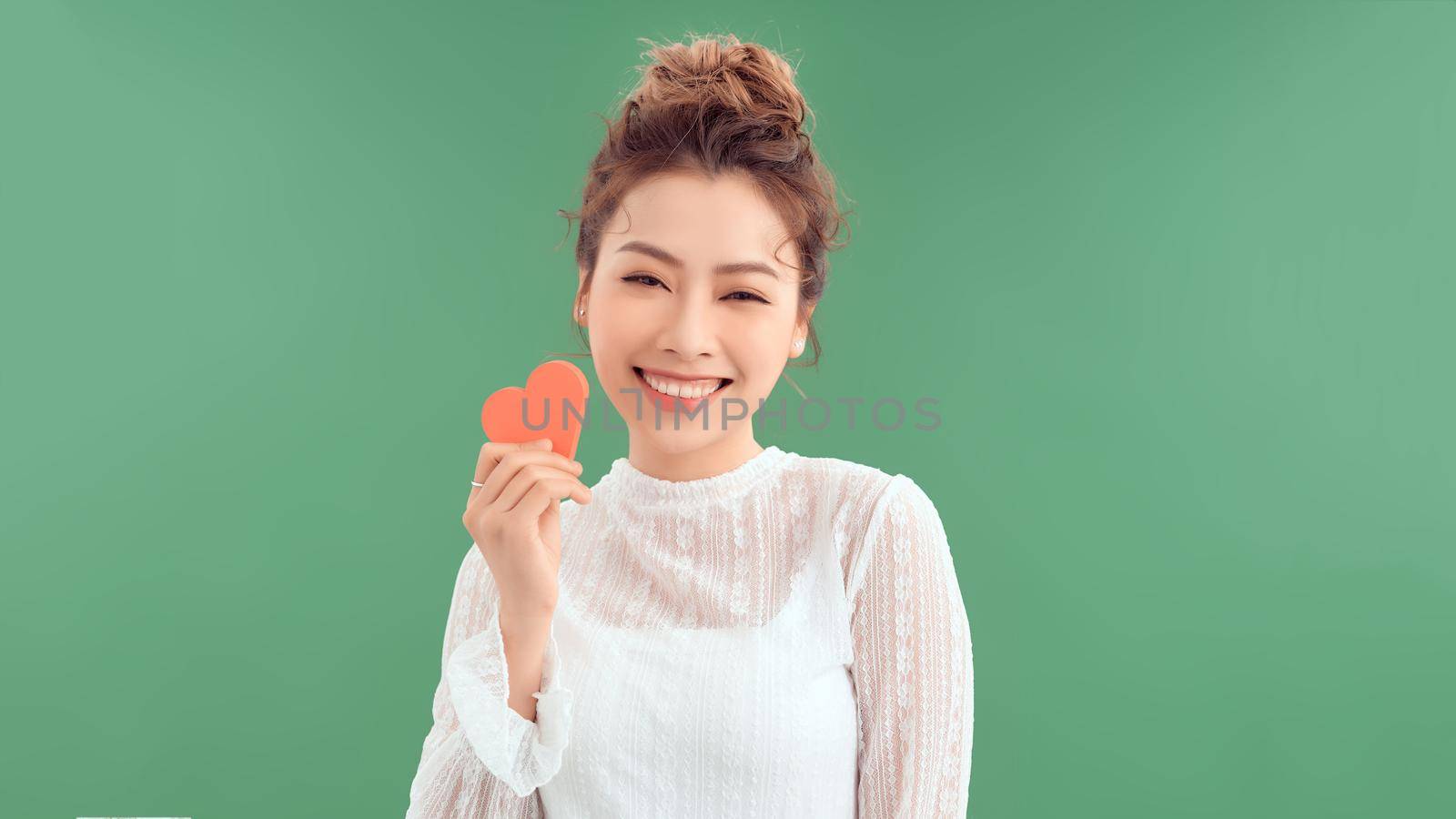 Beautiful asian girl with a heart, Valentine's Day, isolated on green background