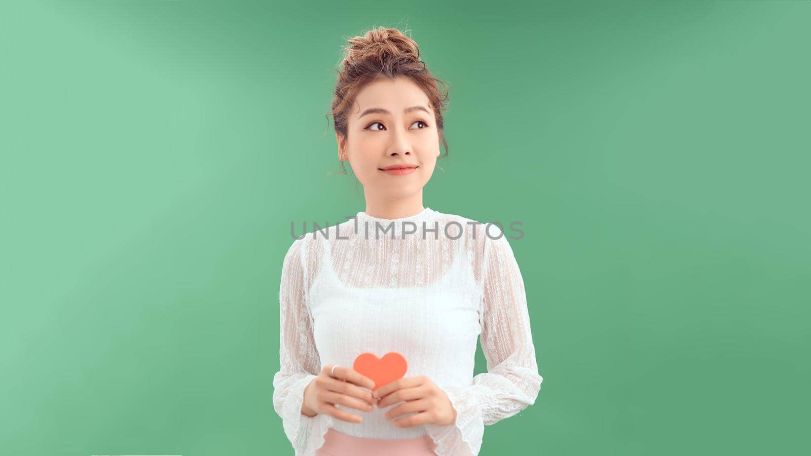 woman holding heart paper valentites card in green background