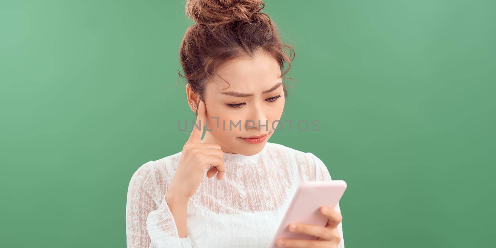 Young woman using smartphone serious face thinking about question, very confused idea