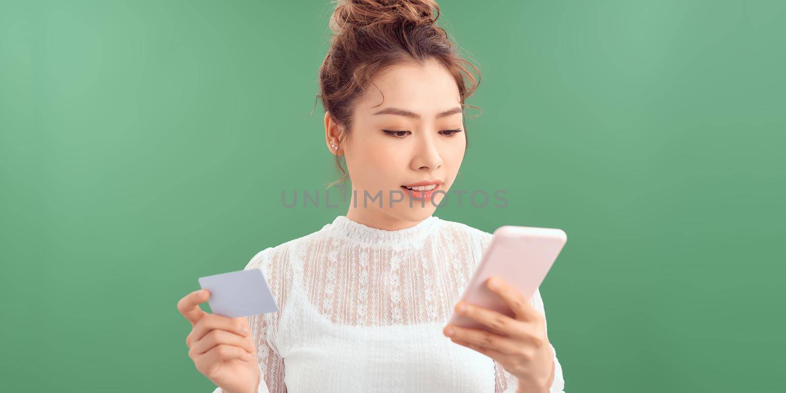 Smiling girl holding phone and credit card. Shopping online concept.