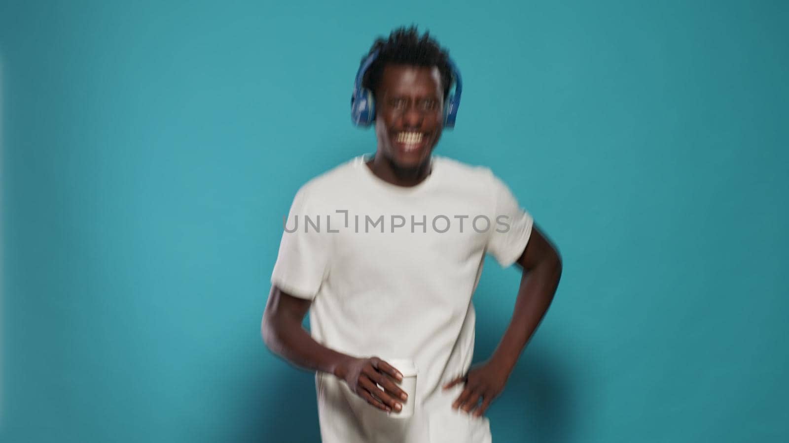 Portrait of man with headphones jumping and dancing to song. Playful person listening to music on headset while doing funny moves on song audio. Adult having fun with rhythm and sound