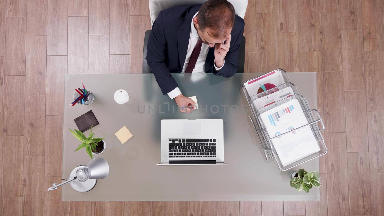 Top view of businessman talking at phone with partner writing corporate profit on stickey notes while working in startup business office. Sccessful director brainstorming management strategy ideas