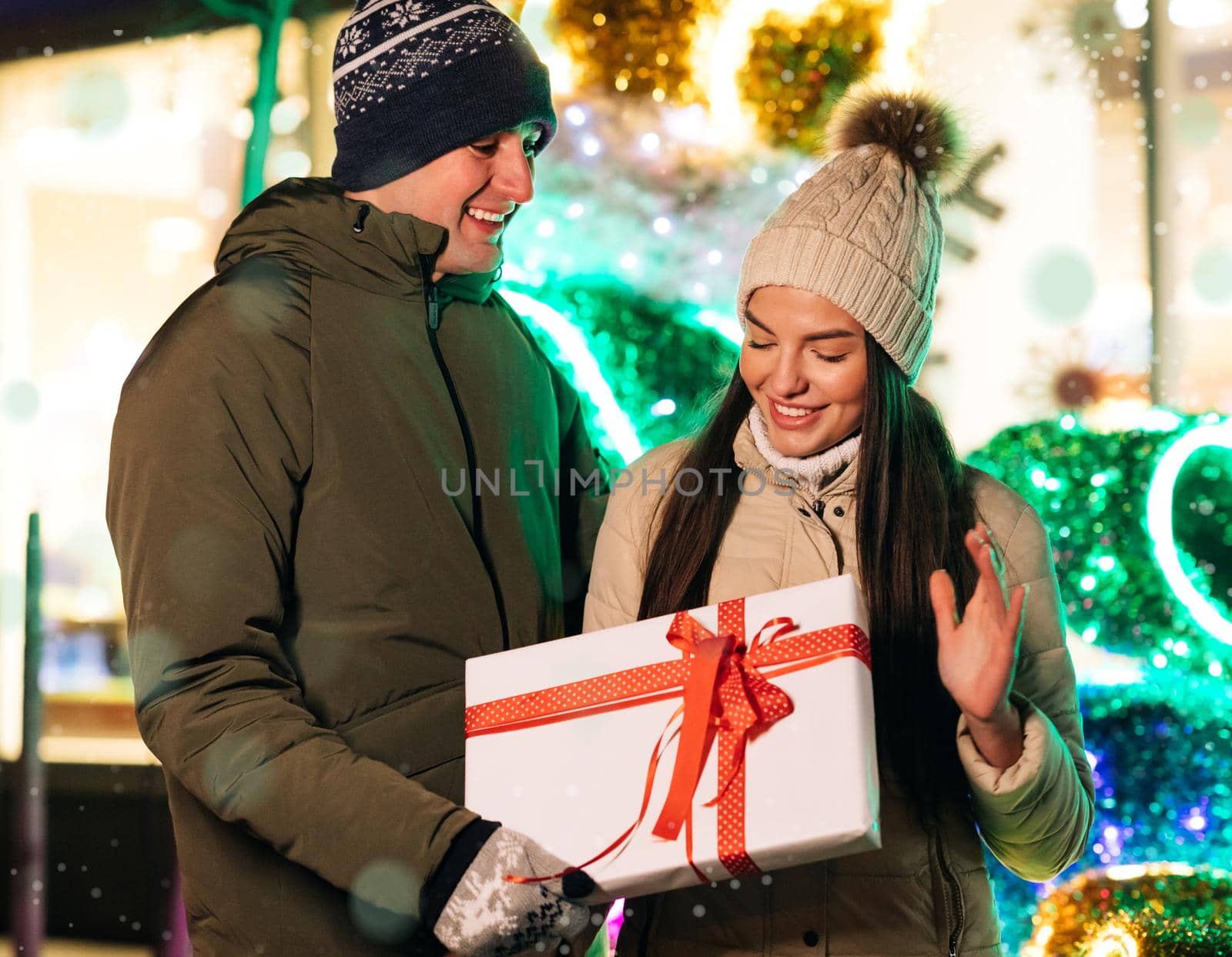 Close up of young beautiful woman hugging man holding Christmas present. Family tradition. Exchange of gifts. Christmas present to beautiful woman.