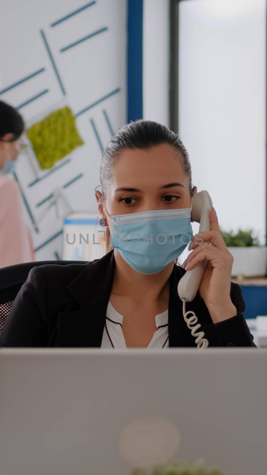 Entrepreneur with protective face mask discussing on landline by DCStudio