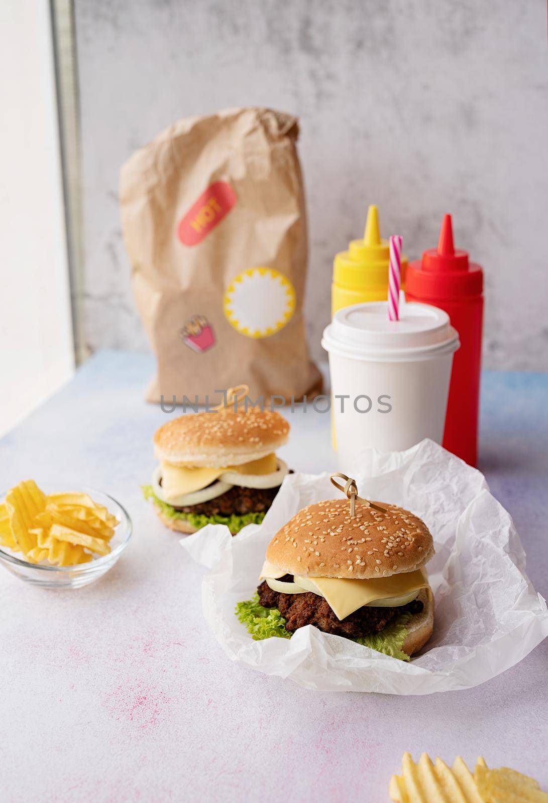 Fat unhealthy food close-up. Set of homemade burgers, chips and drink