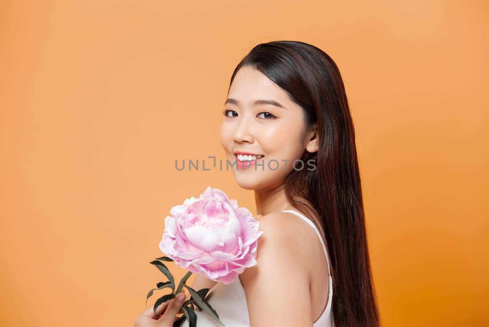 beautiful young woman with pink flower isolated on yellow