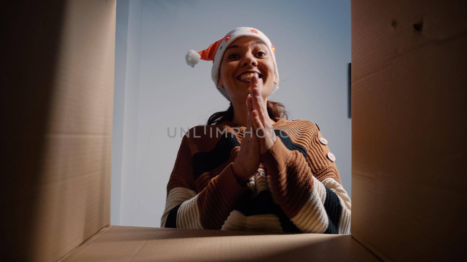 Young person with santa hat looking inside package by DCStudio