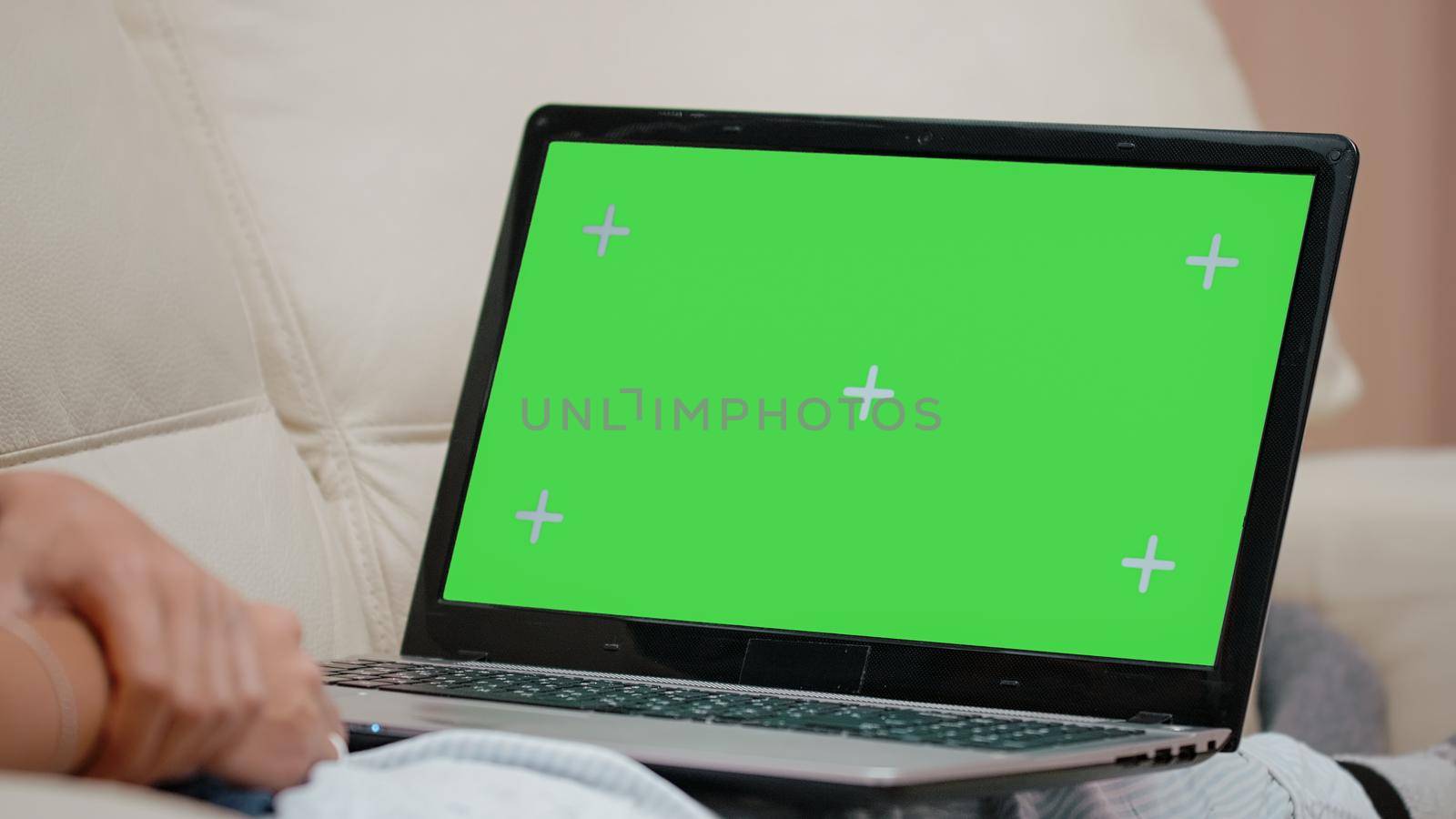 Close up of horizontal green screen on laptop. Person on couch horizontally holding gadget with chroma key screen, mockup template and isolated background. Woman with modern device
