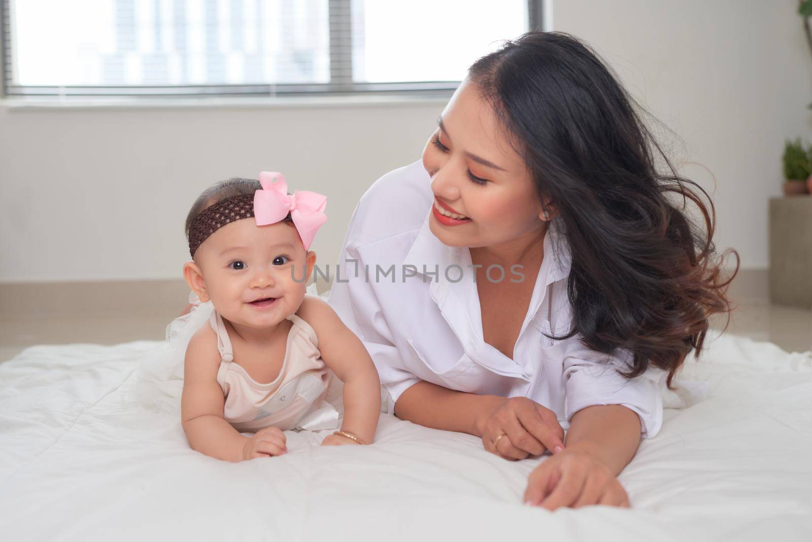 young asian mother and baby lying on floor