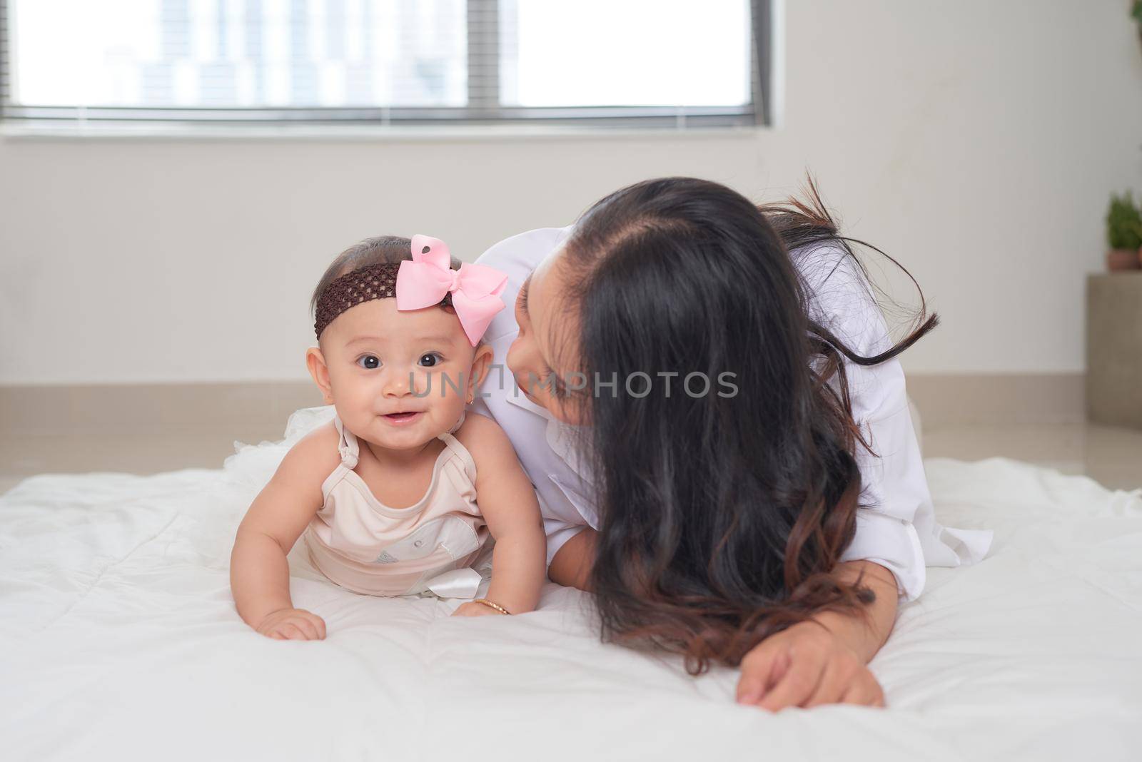 Portrait of a beautiful mother smiling with her baby in bedroom