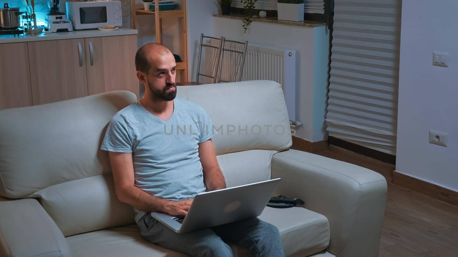 Caucasian male sitting in front of television while working at communication project by DCStudio