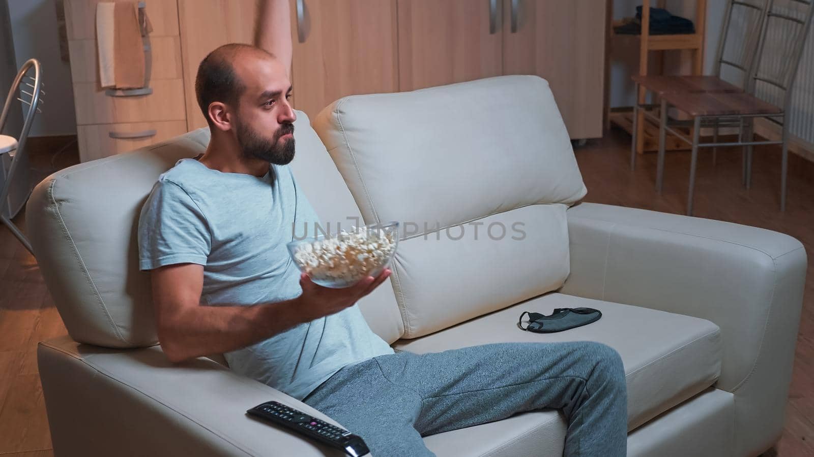 Concentrated man watching entertainment movie while making face expression by DCStudio