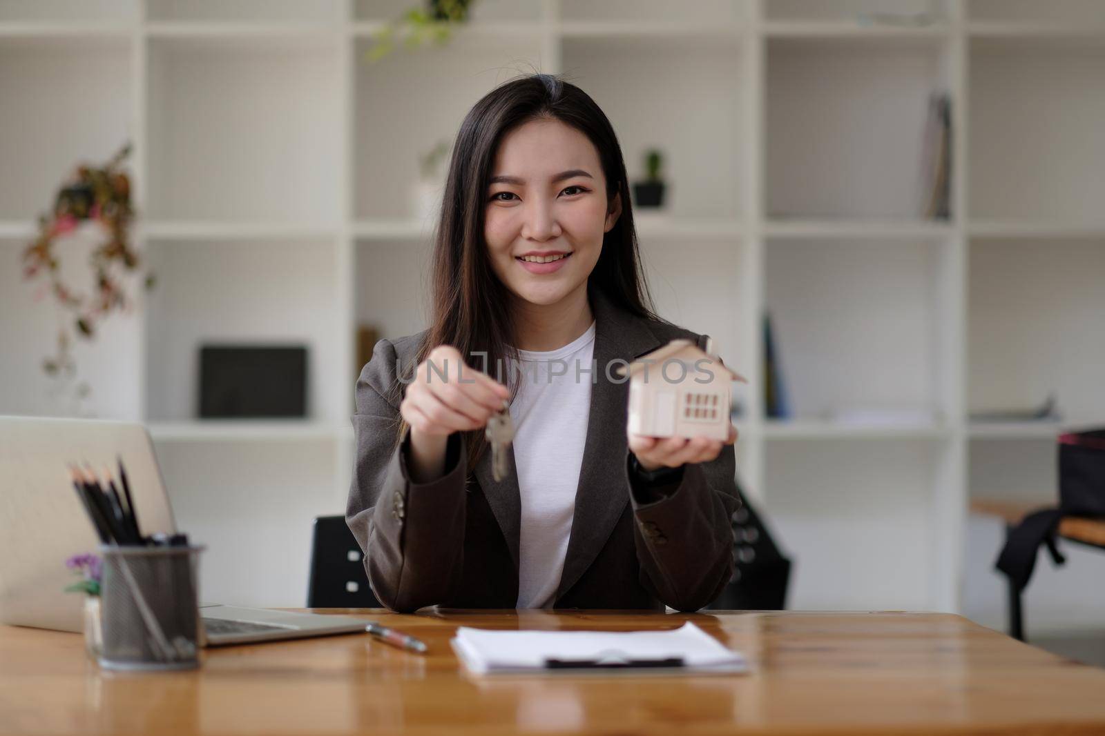 Real estate agent hand holding house model and keys.