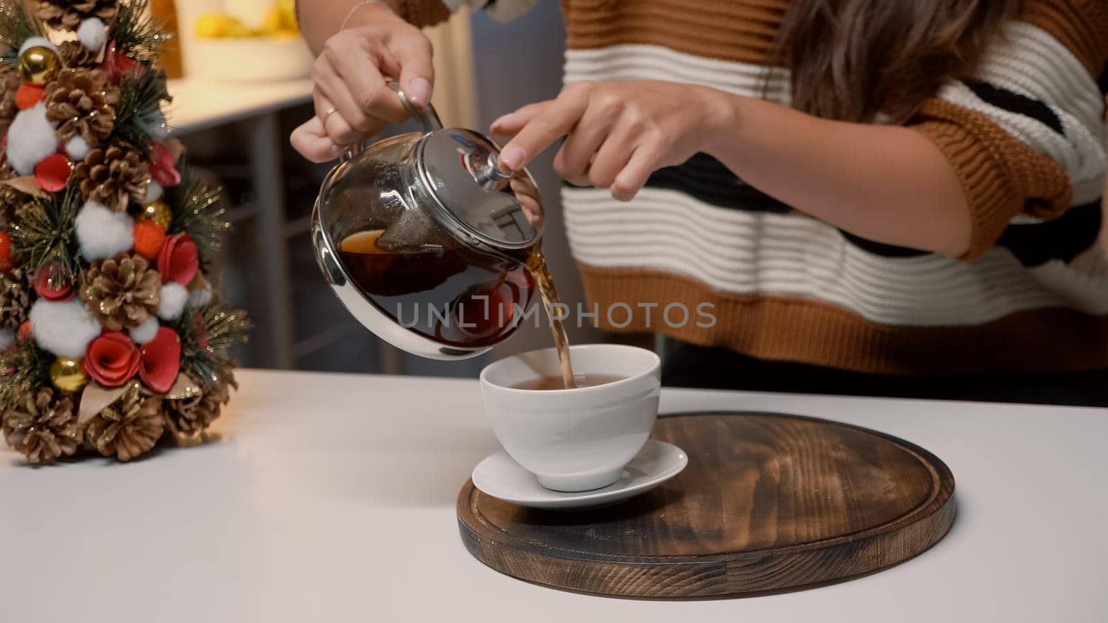 Close up of woman pouring tea from kettle at home by DCStudio