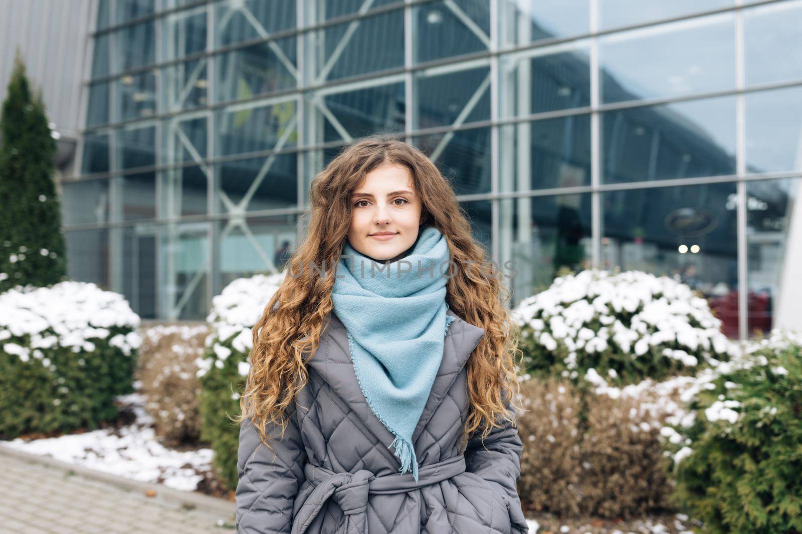 Attractive serious Face young woman looking at camera beautiful curly hair stand on street city lifestyle winter girl city outdoors. by uflypro