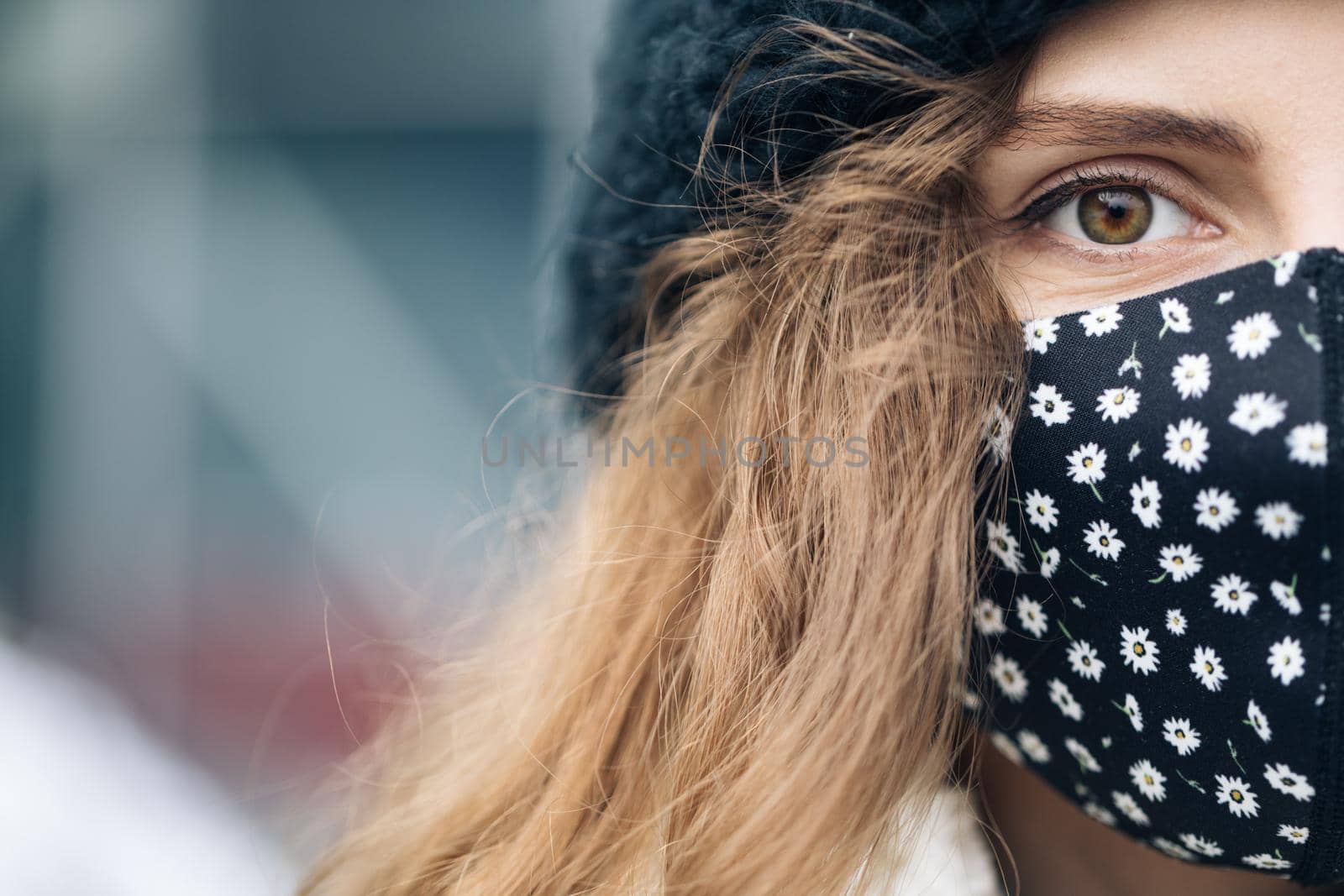 Close up of female half face at street . Portrait of caucasian woman looking at camera. Curly haired woman wears protective mask to avoid contaminating coronavirus. Health and safety concept.