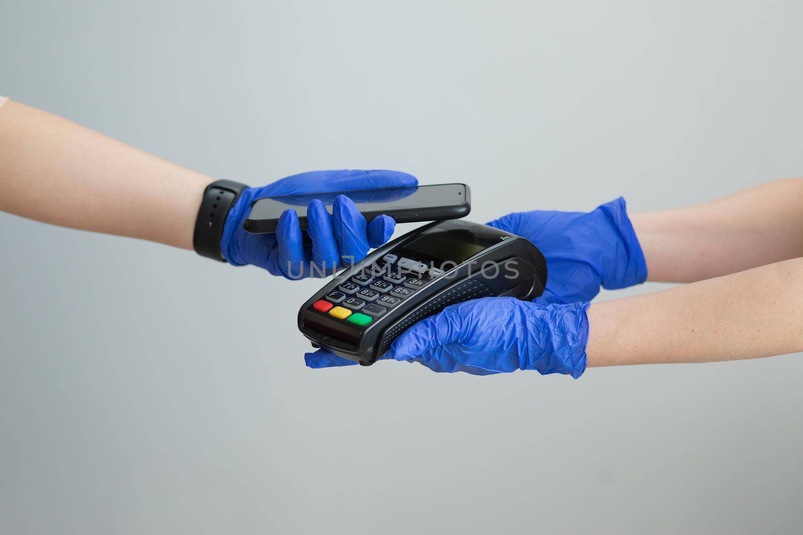 Close-up shot of woman in gloves applies smartphone to terminal performing successful contactless payment. Customer making contactless payment for using paying by smartphone, NFC technology