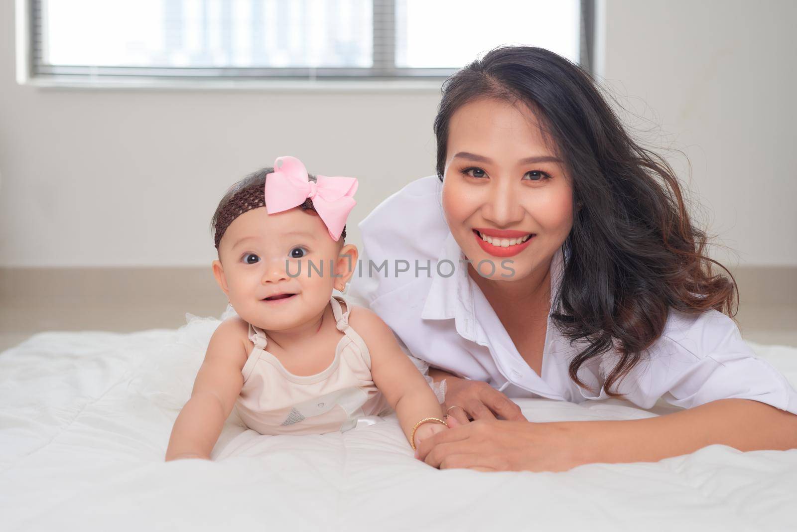 young asian mother and baby lying on floor by makidotvn