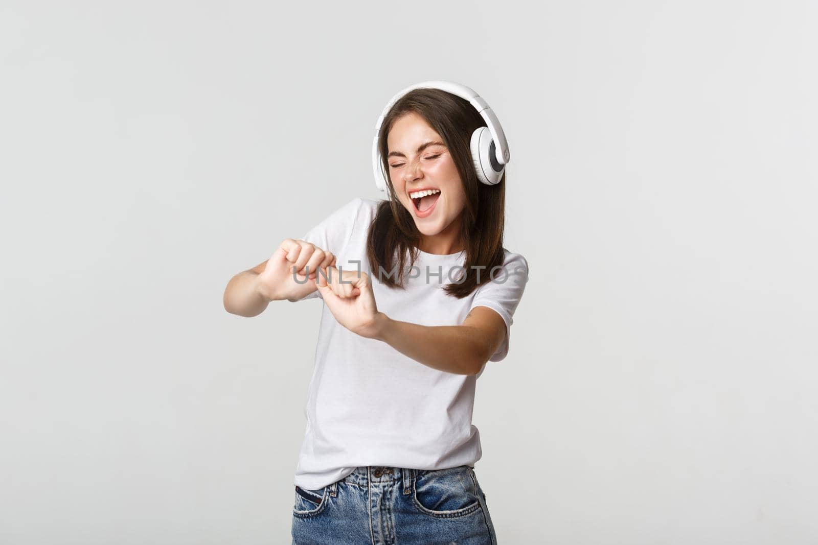 Joyful beautiful young woman dancing, enjoying music in wireless headphones by Benzoix