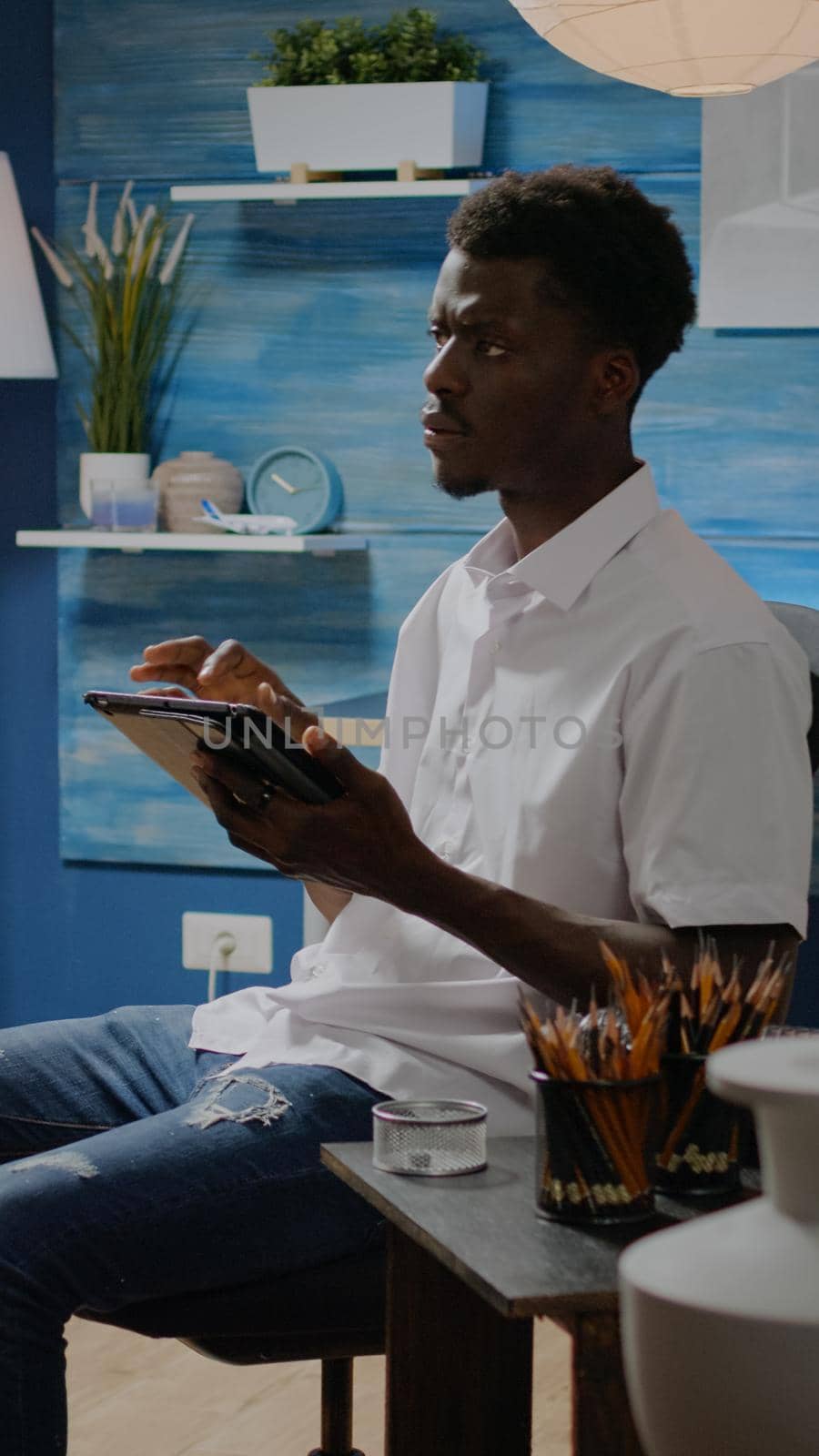 African american artist using digital tablet in artwork studio for fine art inspiration. Black creative man drawing modern masterpiece with technology and design tools. Person with hobby