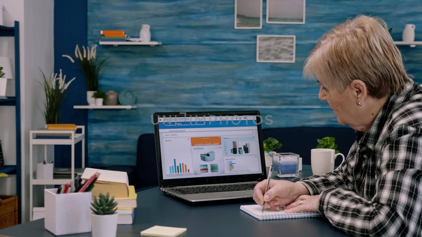 Focused senior entrepreneur checking graphics from laptop by DCStudio