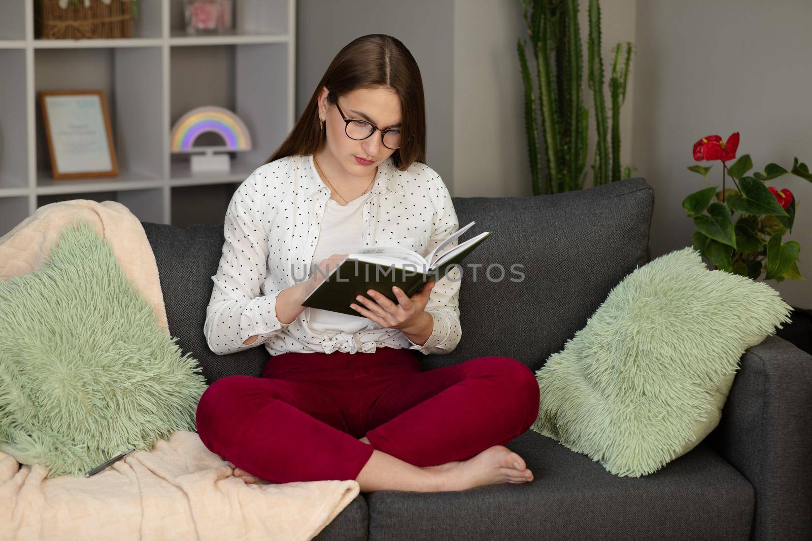 Portrait of a young student reading a book. Beautiful young brunette woman reading a book on the bed at home.