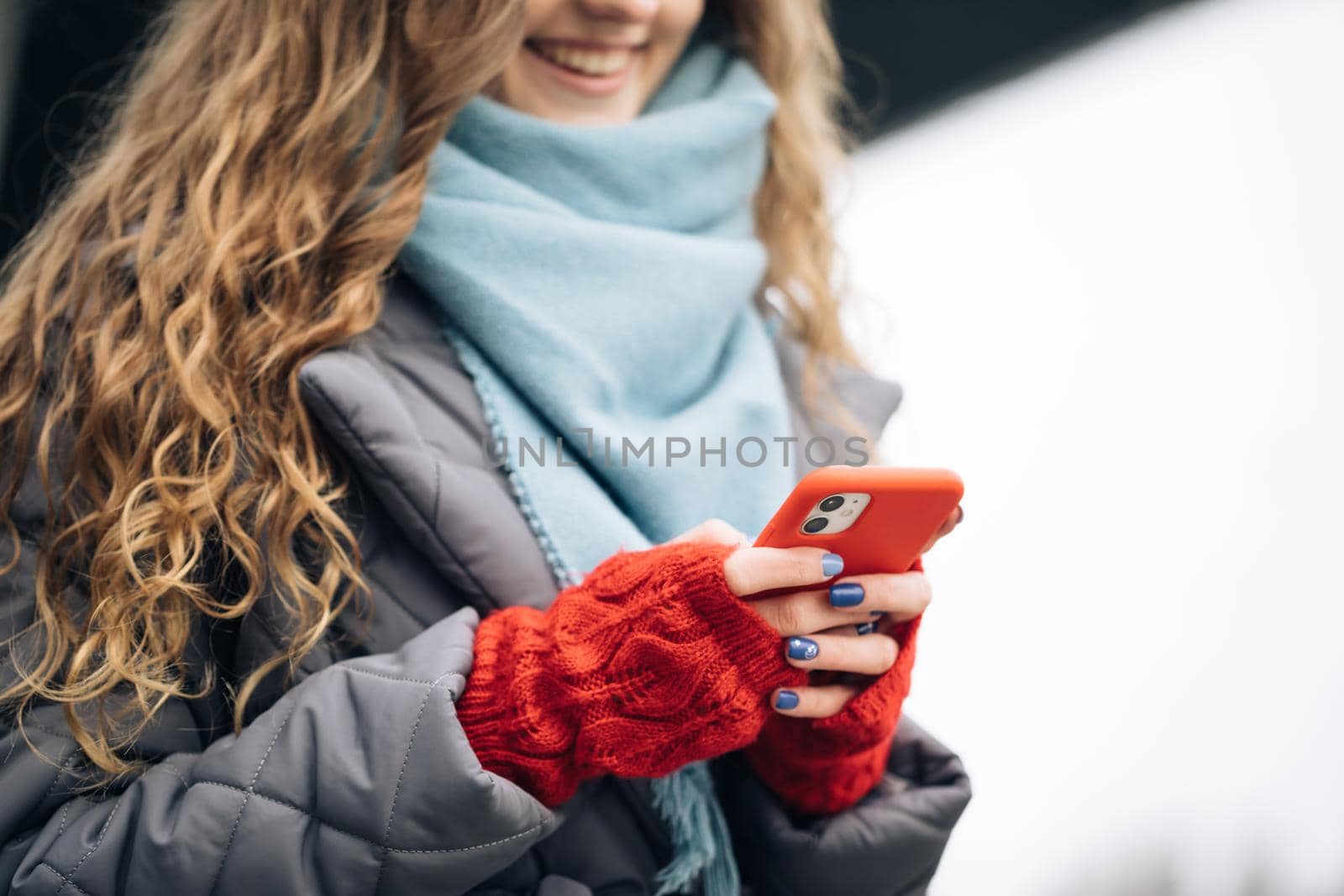Female fingers tapping on cellphone outdoors. Modern holidays online shopping, buying new year's gifts. Close up of woman hands texting on smartphone standing on street in winter city on New Year.