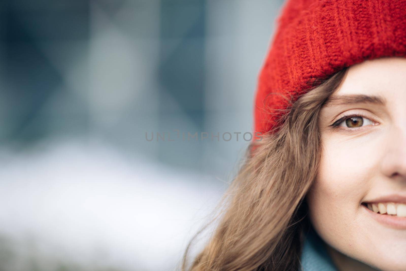Outdoor portrait of attractive urban young woman in stylish winter outfit and red hat smiling to camera. Beautiful charming girl enjoying fashion