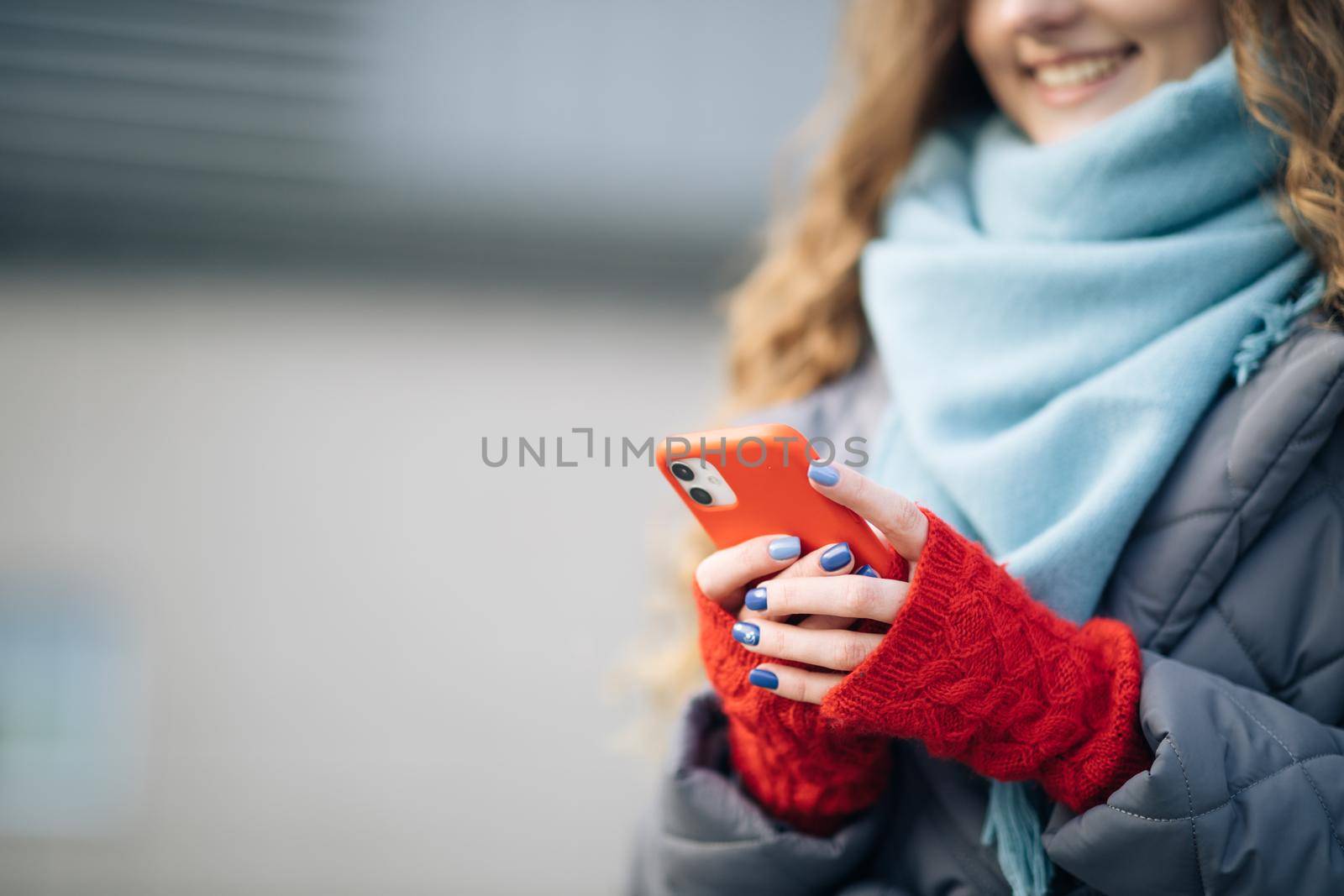 Female fingers tapping on cellphone outdoors. Modern holidays online shopping, buying new year's gifts. Close up of woman hands texting on smartphone standing on street in winter city on New Year.