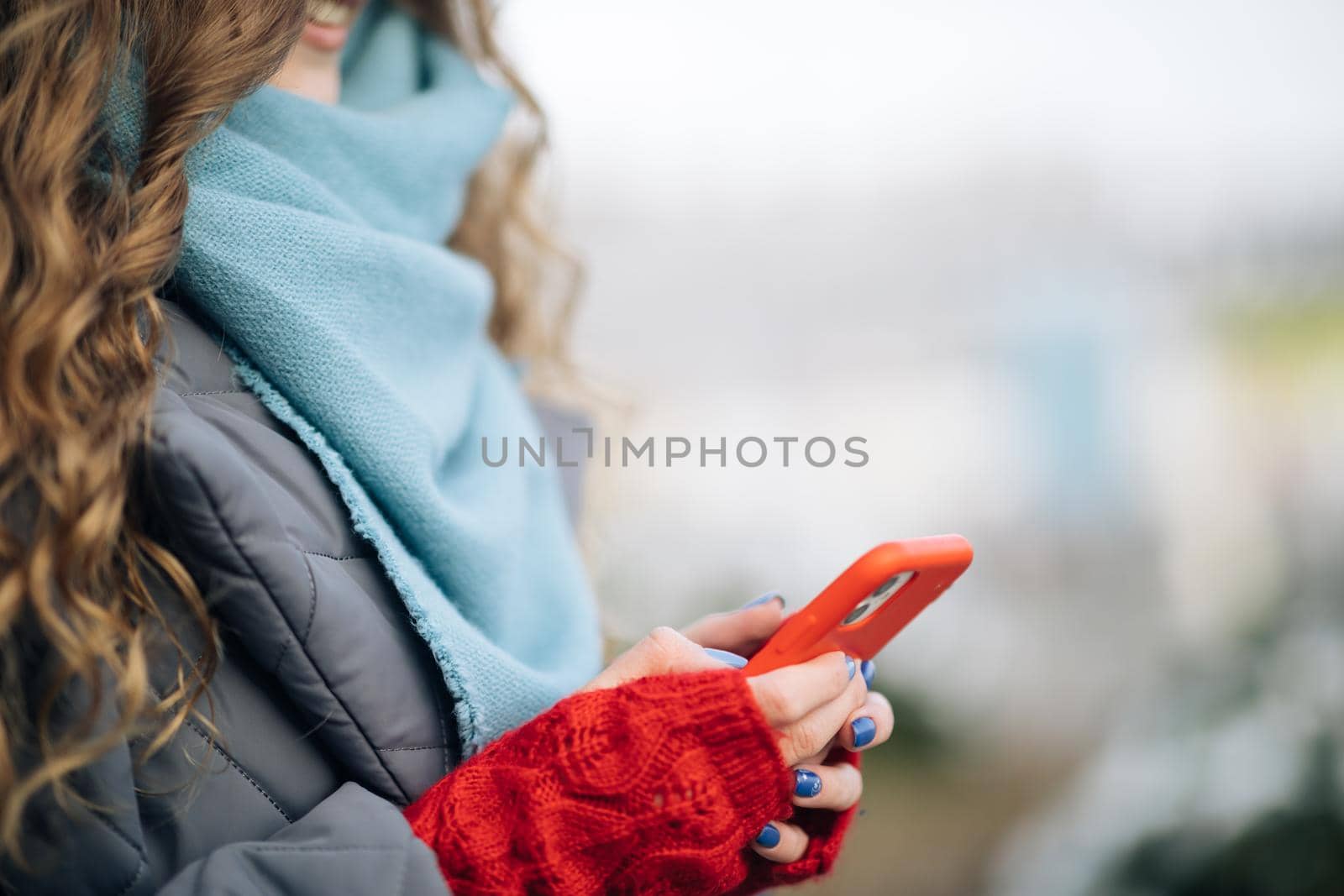 Close up of woman hands texting on smartphone standing on street in winter city on New Year. Female fingers tapping on cellphone outdoors. Modern holidays online shopping, buying new year's gifts.