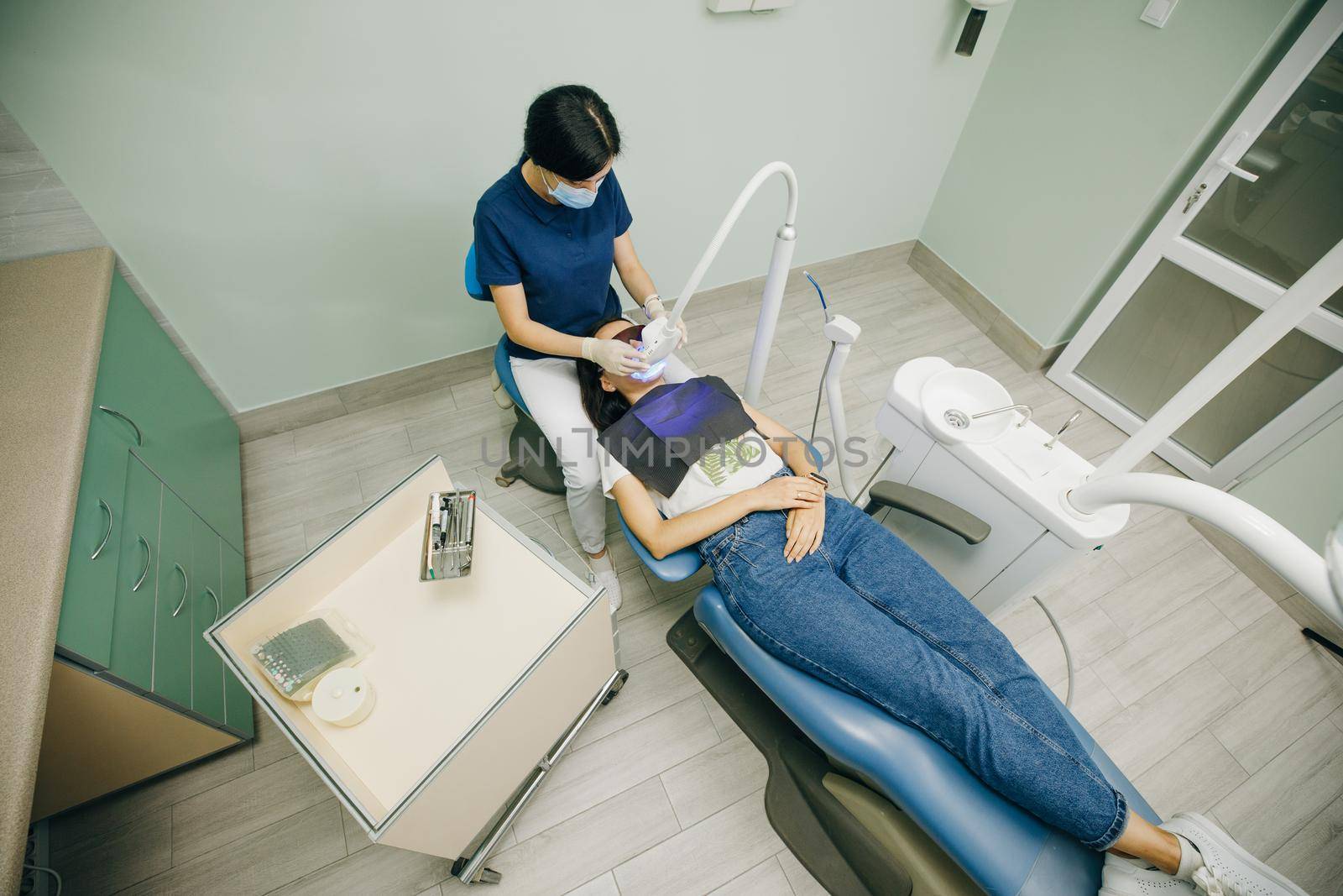 Dentist doing teeth whitening procedure with ultraviolet lamp. Concept of teeth care and dentistry. Led teeth whitening. Ultraviolet rays. Lamp for teeth enamel whitening. Beautiful smile