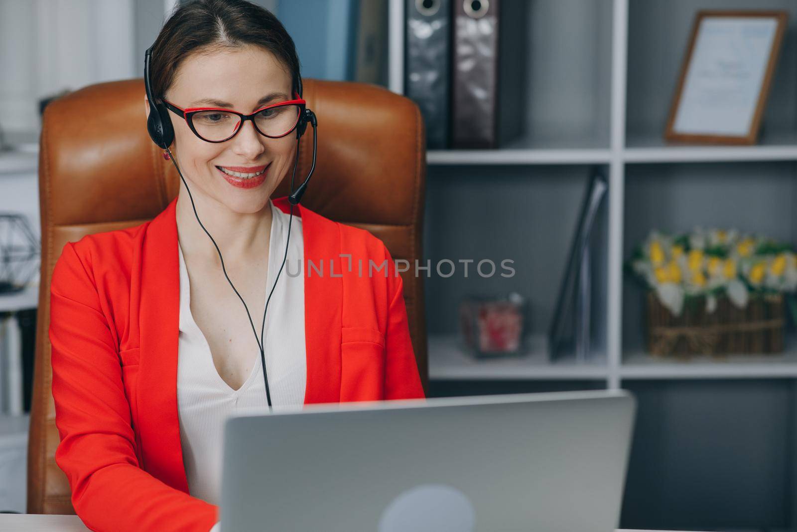 Customer service manager speaking to webcam communicating in distance remote chat in home office. Confident female office worker wears headset, conference video calling, looking at laptop, computer by uflypro