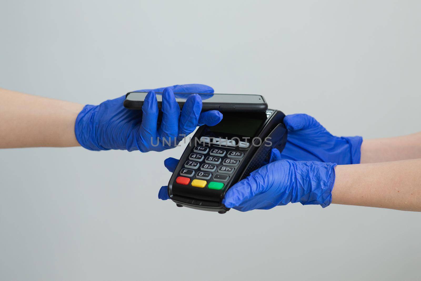 Nfc cellhone of female buyer with cashless wallet of e-money for pos card reader and checkout. Woman in gloves applies smartphone to terminal performing successful contactless payment. by uflypro