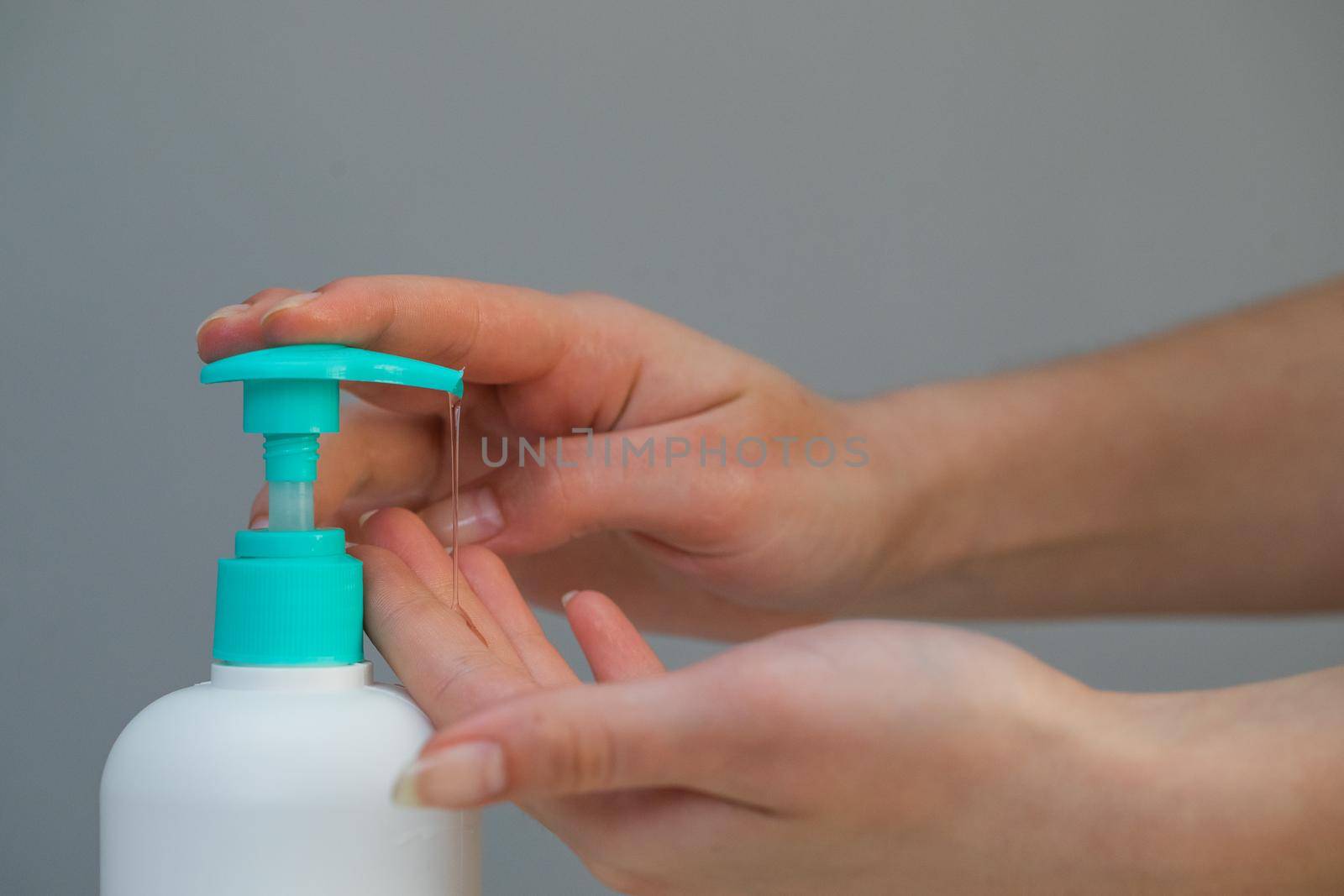 Woman Hands using wash hand sanitizer gel pump dispenser. Clear sanitizer in pump bottle, for killing germs, bacteria and virus by uflypro